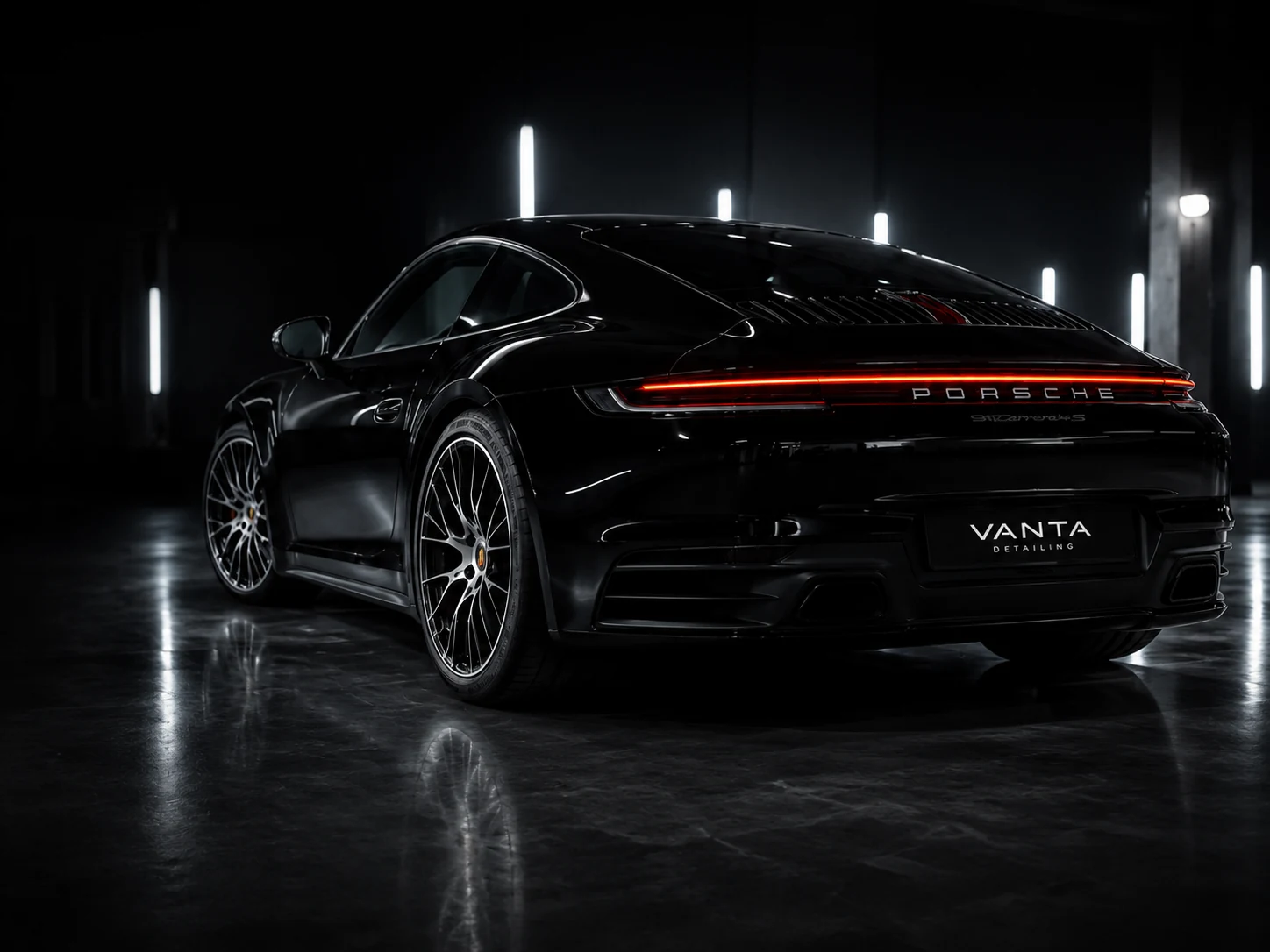 Czarne Porsche w ciemnym studiu detailingowym o filmowym oświetleniu